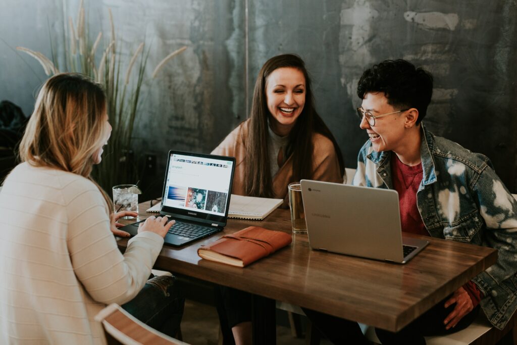 Une réunion où trois personnes sourient autour d'un chef de projet SEO